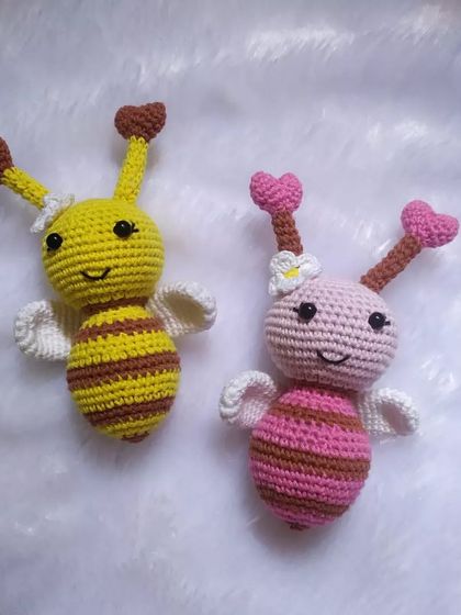 A sweet pair of honeybee toys, one in classic yellow and one in pink. They both have little heart-shaped antennae and tiny wings.