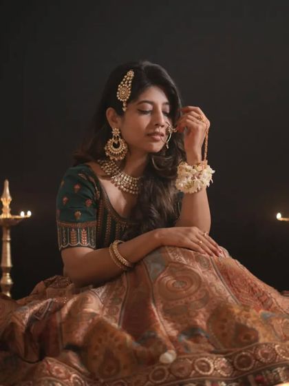 Lost in thought, our model showcases the quiet elegance of this traditional lehenga. The diyas in the background add to the classic, festive mood.