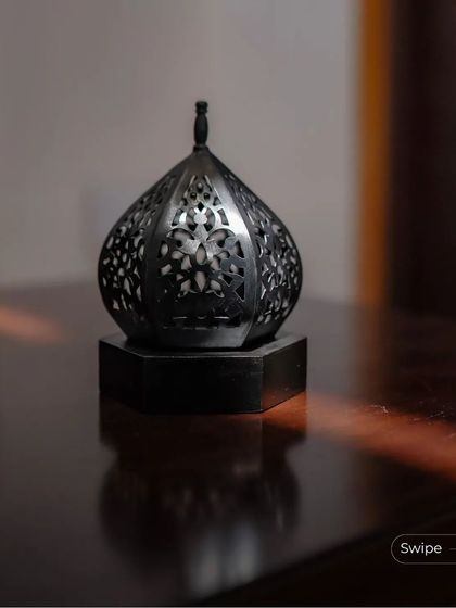 An ornate metal lantern sits on a wooden table, catching a sliver of sunlight. This small decorative element adds a touch of traditional craft to the modern interior.