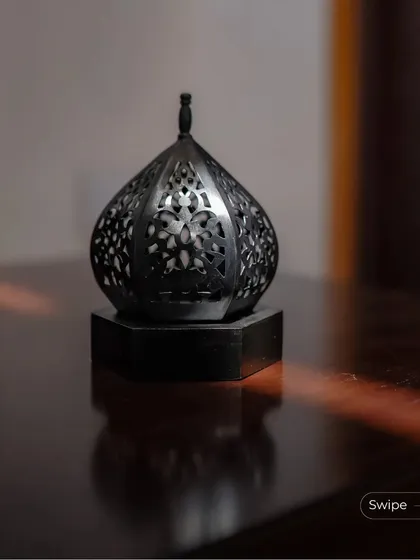 An ornate metal lantern sits on a wooden table, catching a sliver of sunlight. This small decorative element adds a touch of traditional craft to the modern interior.