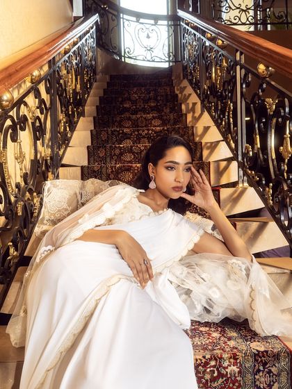 An elegant shot on a grand staircase, featuring a white gown with delicate lace details. The setting and styling combine to create a timeless and romantic image.