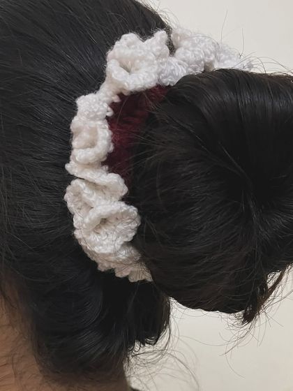 The red and white ruffled hairtie styled around a bun, showing how it adds a touch of handmade charm.