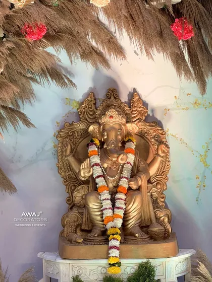 A close-up of the beautiful golden Ganesha idol, adorned with a fresh flower garland.