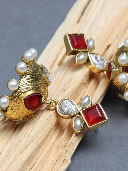 A detailed shot of our copper jhumka with red polki and kundan stones. The combination of materials and the hand-fixed pearls showcase our commitment to quality and native craftsmanship.