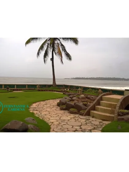 This beautiful seafront villa garden is one of our pride and joy projects. We designed a landscape with a mix of durable lawns, salt-tolerant plants, and hardscaping elements like this stone path and bridge that withstand the coastal climate.