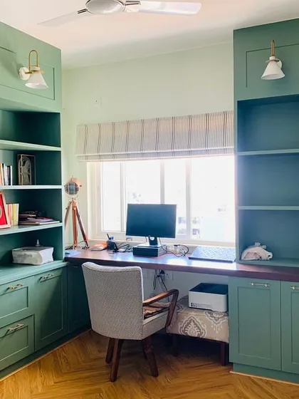This isn't your average boring office. We designed this workspace with custom-built green cabinetry, integrated shelving for books and decor, and a large window for natural light, creating a productive and inspiring environment.