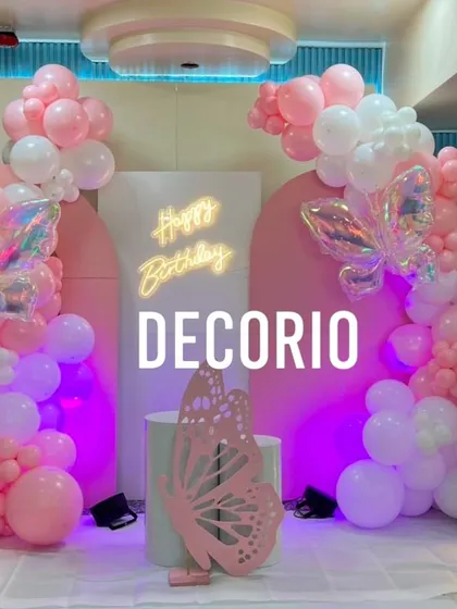 A beautiful butterfly-themed 6th birthday party in shades of pink and white. The decor features iridescent butterfly accents, a 'Happy Birthday' neon sign, and a '6' marquee number.