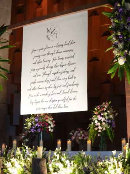 A personalized photo booth featuring a canvas with the couple's story, surrounded by candles and floral arrangements.