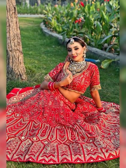 A full-length shot of the bride sitting on the grass, showcasing her entire outfit.