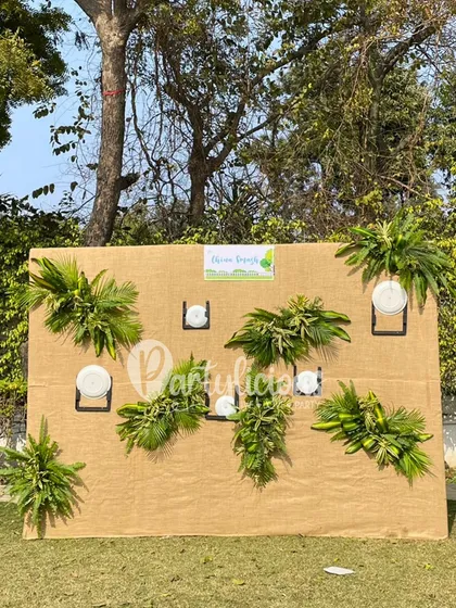 A unique and eco-friendly plate display wall for a jungle-themed party, using natural jute backing and fresh greenery.