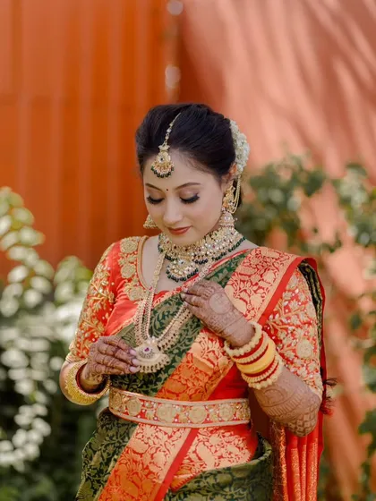 A closer look at the intricate details of the temple jewellery set, showing how the bride adjusts her stunning long necklace, or rani haar.