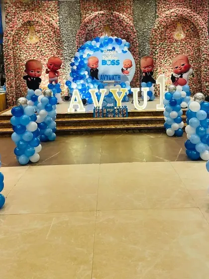 A grand Boss Baby setup in a banquet hall, featuring a circular backdrop, character standees on balloon pillars, and large marquee letters.