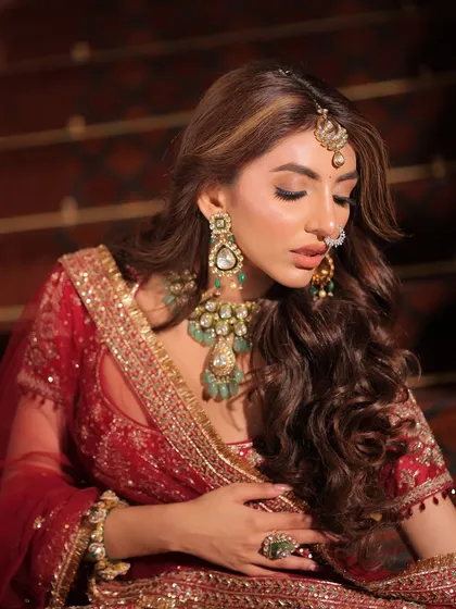 This image captures the bride's serene expression and the beautiful details of her maang tikka and nose ring, essential elements of the traditional bridal look.