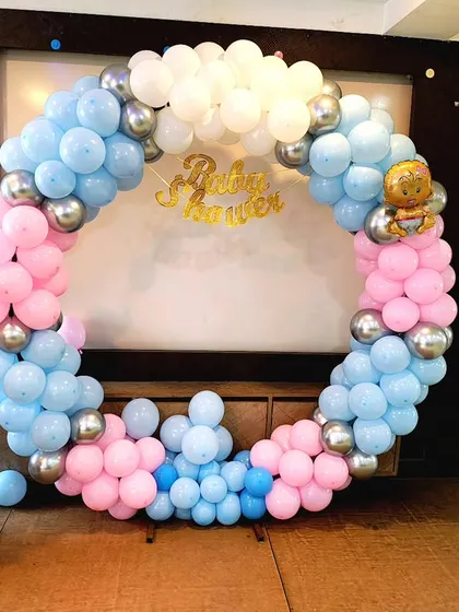 This is a classic baby shower decoration with a full circular balloon arch in pink and blue. The setup also includes 'BABY' display boxes, making it a great photo corner for the parents-to-be.