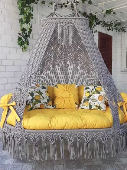 A grey sofa swing with bright yellow cushions. The lemon-print pillows and side bows add a cheerful and summery vibe to this versatile piece.