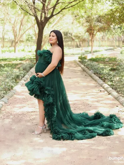A full-length shot of the mom-to-be on the park path, showcasing the dramatic train of her emerald green gown. This is a great example of our glamorous outdoor maternity photography.