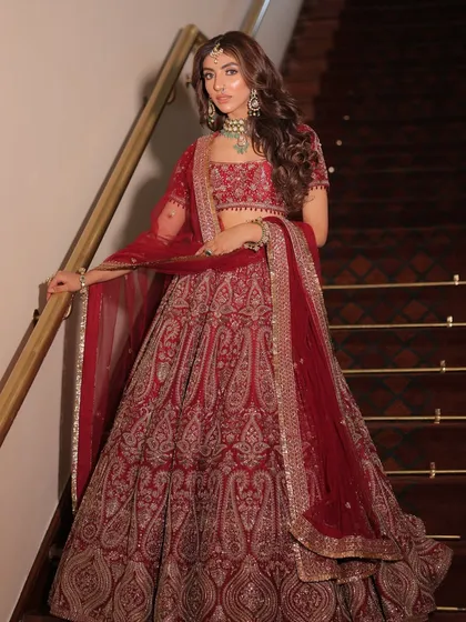 A full-length shot of a bride in a deep red lehenga by Kajal Rajput. I styled this to feel both traditional and modern, with a focus on the paisley motifs and the flowing silhouette.