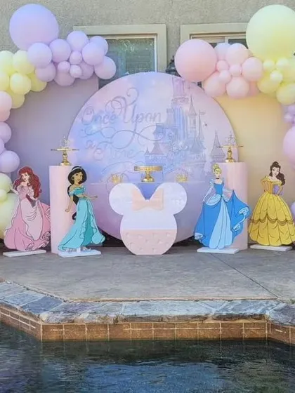 A poolside princess party setup. This "Once Upon a Time" theme uses pastel balloons and cutouts of different princesses to create a fairytale setting.