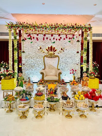 A beautiful all-white floral backdrop with red accents creates a very elegant and classic look. This setup for a baby shower combines a traditional frame with a modern color palette, complete with detailed plate arrangements and dolls.