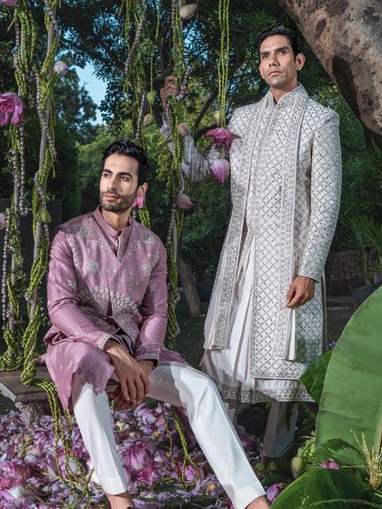 An elegant pairing of a classic white sherwani and a contemporary mauve kurta set. This showcases our ability to outfit the entire wedding party with distinct yet harmonious styles.