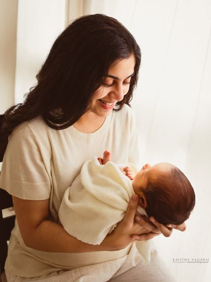 A new year, a new beginning. A mother smiles at her newborn, a beautiful and hopeful portrait captured in the soft light of a window.