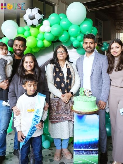 A beautiful family portrait in front of the green and silver balloon decor at the football-themed party.