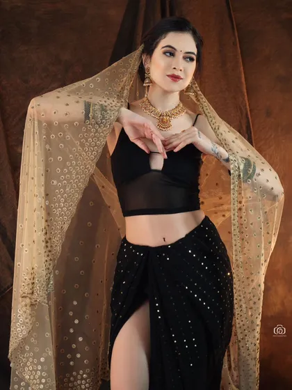 A beautiful portrait capturing the elegance of an Indo-western fusion look. The model's pose and the way she holds the sheer dupatta create a sense of grace and movement.