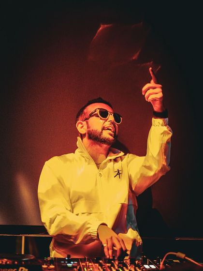 A cool, stylized shot of me at the console, with a yellow jacket and sunglasses, ready to drop the next track.