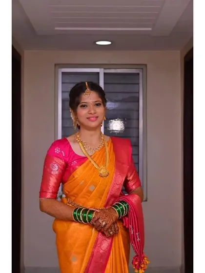 A bright and beautiful look for a wedding guest. The makeup is kept fresh and radiant to complement the vibrant colors of her orange and pink saree, ensuring she looks her best throughout the event.