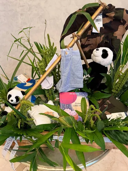I love creating entire worlds within a gift hamper. For this baby announcement, I designed a complete panda jungle, using bamboo stalks, lush greenery, and themed clothes and books to tell a whimsical story for the new arrival.