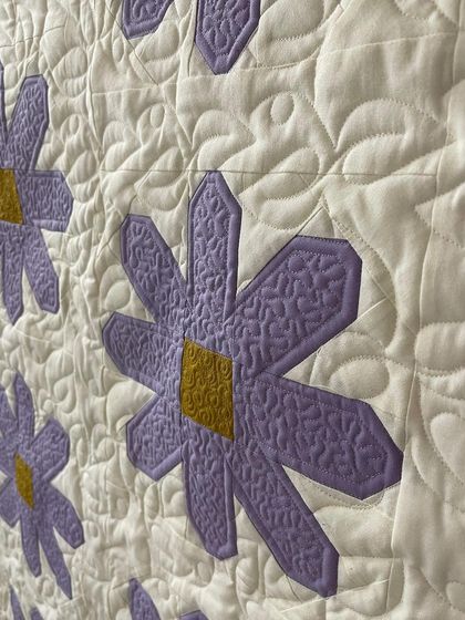 A close-up of the daisy quilt, showing the texture inside the flower petals and the detailed background quilting.