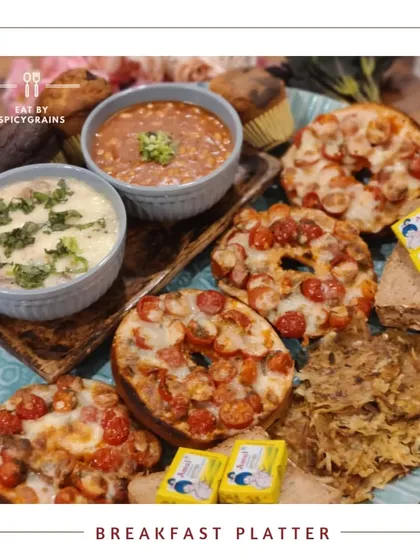 A hearty and delicious Breakfast Platter. This spread includes pizza bagels, muffins, parathas, and dips, offering a mix of Indian and continental flavors to start the day right.