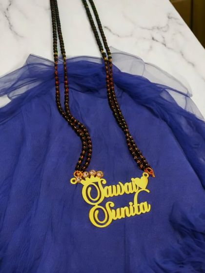 A customized double-name pendant with a crown detail, set on a long, double-stranded mangalsutra chain. This piece makes a bold and personal statement.