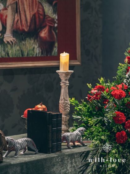 A detail of a tabletop vignette, featuring vintage books, candles, and small tiger figurines, adding a touch of whimsy to the classic, artistic theme.