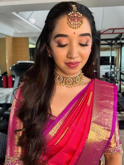 A festive look for Ganesh Pooja, featuring a bright pink silk saree and traditional gold jewelry.