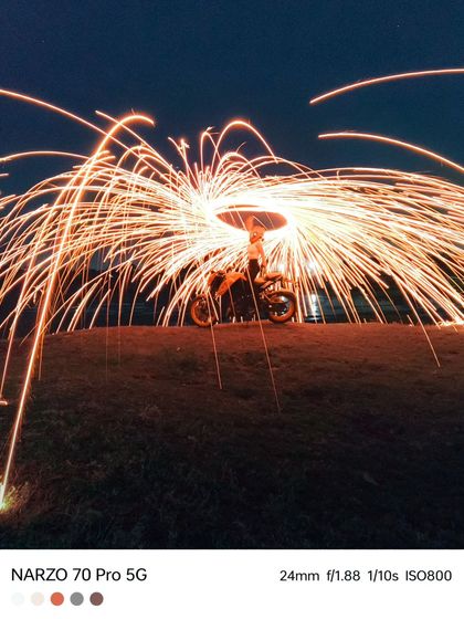 A wide shot showing the full effect of the steel wool sparks raining down, all captured with the long exposure mode on a smartphone.