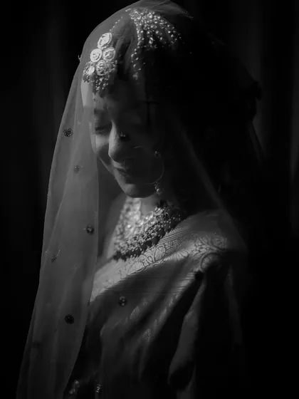 A soft and ethereal black and white portrait of a bride under her veil, capturing a moment of quiet grace.