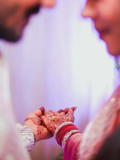 The moment of the ring exchange, captured in an intimate, over-the-shoulder shot. The focus is on their hands and the ring, symbolizing the official start of their journey together.