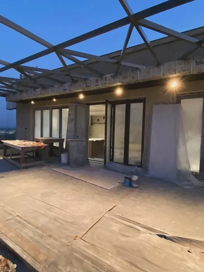 This is a behind the scenes look at a large terrace project in progress. You can see the metal framework for a glass roof being installed, an architectural feature that will create a stunning, all-weather outdoor living area.