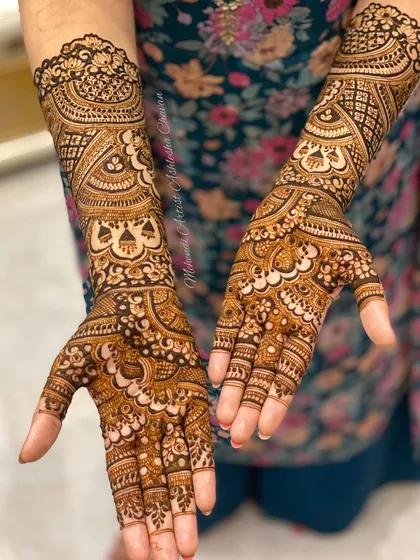 A full-coverage mehendi design with a mix of traditional Indian and Arabic styles. The patterns are intricate and flow beautifully from the fingers to the arms.
