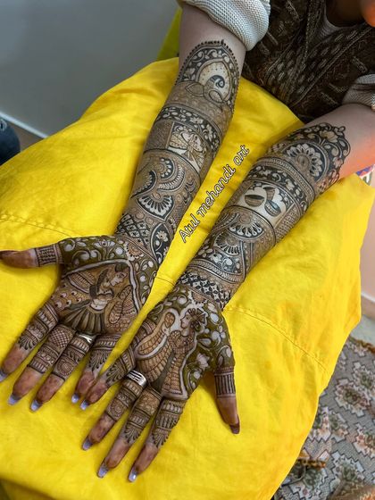 The full view of the personalized bridal mehandi, with portraits on the palms and custom motifs on the arms.