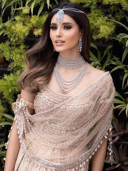A soft and ethereal look, perfect for a reception or engagement. The makeup is luminous and glowing, with a focus on highlighting the skin, paired with a beautiful beige lehenga and diamond jewellery.