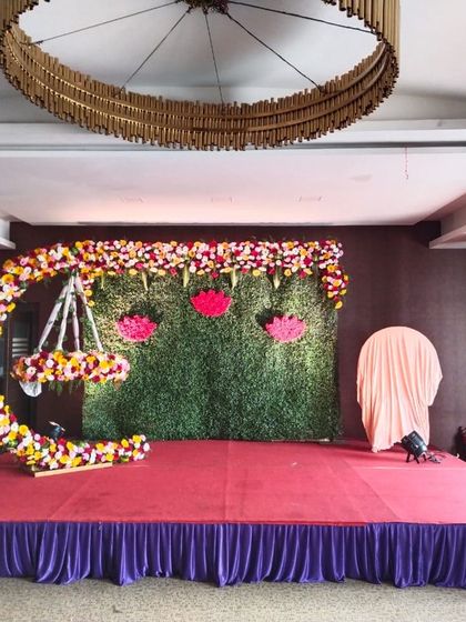 A wide shot of our lotus-themed naming ceremony stage. The floral crescent moon cradle is the centerpiece, complemented by elegant floor-standing flower arrangements.