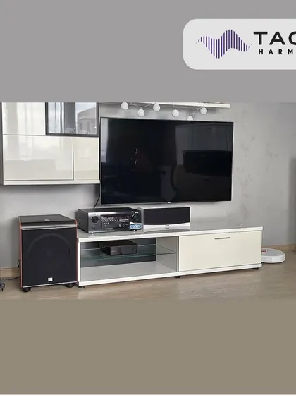 A clean and modern living room setup featuring Taga Harmony tower speakers in white. This system provides a full-range audio experience for both music and movies, integrating well with the contemporary furniture.