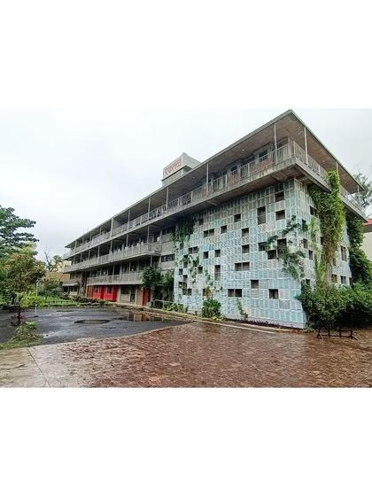 The full facade of the Eklavya campus, showing the unique wall of reclaimed windows. Over time, nature has begun to claim the structure, with creepers growing up the wall, fulfilling our vision of a building that coexists with biodiversity.