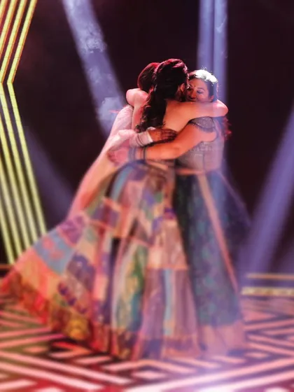 An emotional, soft-focus shot of a group hug on the dance floor during the reception, capturing a moment of love and friendship.