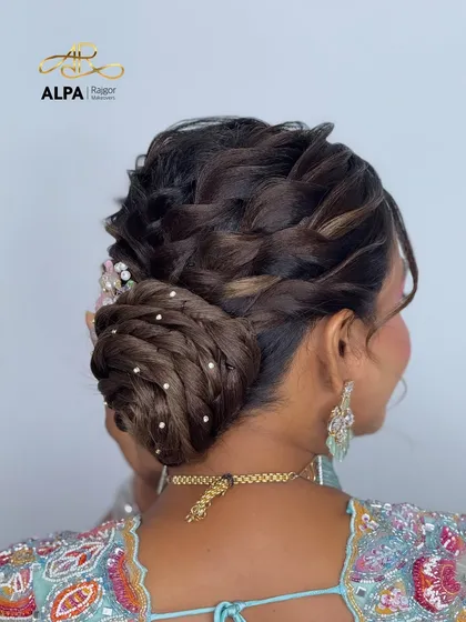 A back view of a braided bun, intricately woven and decorated with small pearl accessories for a touch of class.