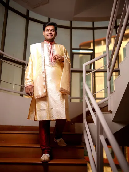 A full-length shot of the groom descending a modern staircase. This portrait captures his style and the anticipation of the wedding day.