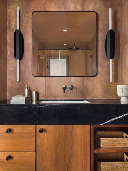 Another bathroom in the East Coast Residence, featuring a black marble countertop and modern, sculptural wall sconces. The design is clean and contemporary, with a focus on high-quality materials.