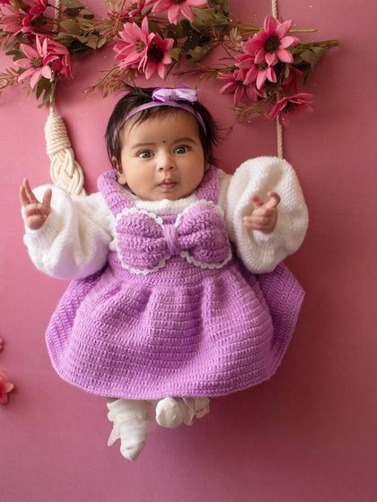 This two-month-old baby is wide awake and looking right at the camera from her floral swing. Her bright eyes are just captivating.